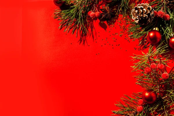 赤い背景にクリスマスツリーの枝 コーンや装飾品 フラットレイアウトスタイル 新年の旗 — ストック写真