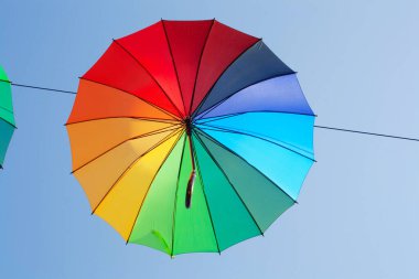 Mavi gökyüzüne karşı çok renkli bir şemsiye. Sonbahar konsepti, yağmur