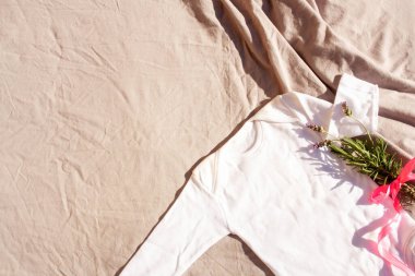 Gri arka plan manzaralı beyaz bir bebek tulumu ve lavanta. Modelleme. Güneşli bir gün Gölgeler arası moda trendi