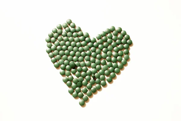 Stock image Spirulina tablets in the shape of a heart on a white background. Flat lay style.