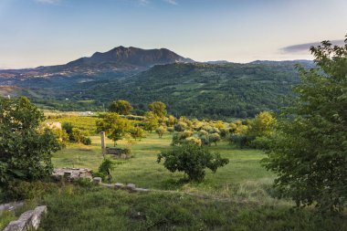 Taurasis 'in sakin manzarası alacakaranlıktaki yemyeşil kayan tepeler ve uzak dağ sıraları.