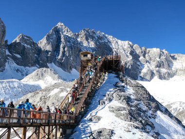 Trestle Tahta Köprü Yolu 'nda yürüyen turistler, Lijiang, Yunnan, Çin' deki Yeşim Ejder Kar Dağı 'nın tepesini ziyaret edip eğleniyorlar.  