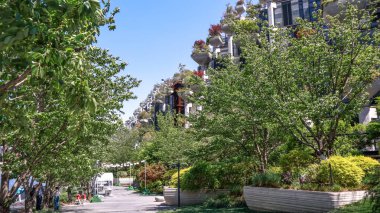 Çin 'in Şangay kentindeki ikonik Tian An 1000 Trees binasının önündeki şehir parkında açık mavi gökyüzü altında yemyeşil ve yenilikçi dikey orman mimarisi sergileniyor.