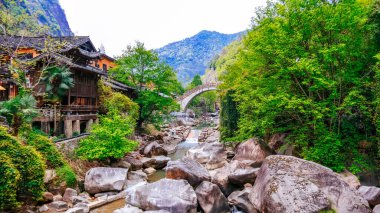 Geleneksel taş kemer köprüsü manzarası ve Çin 'in Shangrao şehrindeki Wangxian Vadisi' ndeki kayalık dere boyunca tarihi ahşap evler.