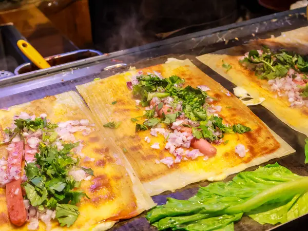 Sosis, doğranmış soğan, kişniş ve yumurtayla dolu taze Çin sokak yemekleri katlanıp servis edilmeye hazır.