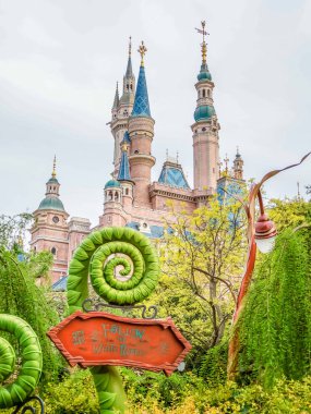 Alice Harikalar Diyarı 'ndaki Maze Bahçesi tabelasında Şangay Disneyland, Çin' deki Büyülü Masal Kitabı Kalesi 'nin önünde lunaparkın fantezi temalı ortamını yakalıyor.
