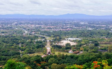 Tayland 'ın Chiang Mai şehrinin panoramik hava manzarası, bir dağ tarafından görülüyor. Dağlarla çevrili kentsel gelişimle yemyeşil bir arazi.