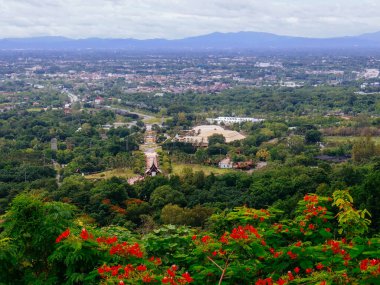 Tayland 'ın Chiang Mai şehrinin panoramik hava manzarası, bir dağ tarafından görülüyor. Dağlarla çevrili kentsel gelişimle yemyeşil bir arazi.