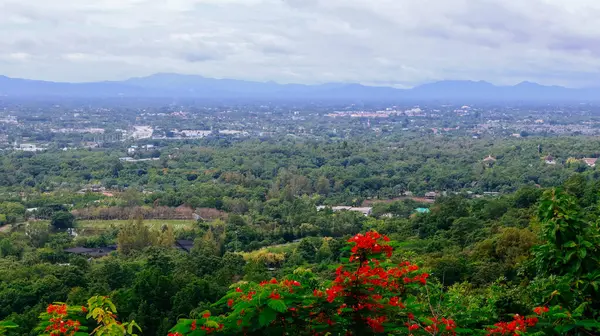 Tayland 'ın Chiang Mai şehrinin panoramik hava manzarası, bir dağ tarafından görülüyor. Dağlarla çevrili kentsel gelişimle yemyeşil bir arazi.