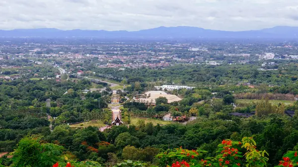 Tayland 'ın Chiang Mai şehrinin panoramik hava manzarası, bir dağ tarafından görülüyor. Dağlarla çevrili kentsel gelişimle yemyeşil bir arazi.