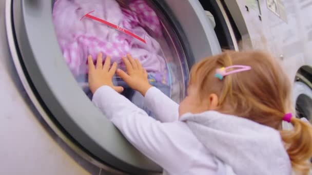 小さな女の子の定期的なハウスキーピングは 洗濯機にタオルを取り出し 居心地の良い洗濯室で現代的な洗濯乾燥機のアプライアンスをオンにします 家事の概念 高品質4K映像 — ストック動画