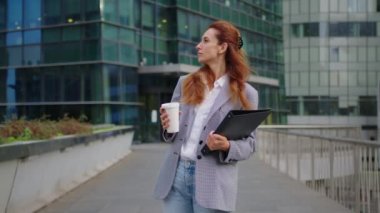 Çekici, kendine güvenen, gülümseyen, çeşitli kurumsal resmi bir kadın ofis binasının önünde duruyor ellerini katlıyor, kameraya bakıyor ve gülümsüyor. Yüksek kalite 4k görüntü