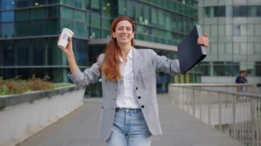Çekici, kendine güvenen, gülümseyen, çeşitli kurumsal resmi bir kadın ofis binasının önünde duruyor ellerini katlıyor, kameraya bakıyor ve gülümsüyor. Yüksek kalite 4k görüntü