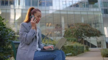 İş kadını ofis binalarının arka planında dizüstü bilgisayar kullanıyor. Yüksek kalite 4k görüntü