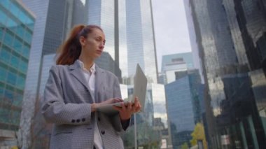 İş kadını ofis binalarının arka planında dizüstü bilgisayar kullanıyor. Yüksek kalite 4k görüntü