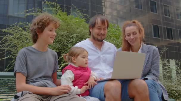 快乐的大家庭父母和小孩喜欢一起坐在户外 和孩子们一起玩笔记本电脑 一起玩人们的小玩意成瘾 高质量的4K镜头 — 图库视频影像