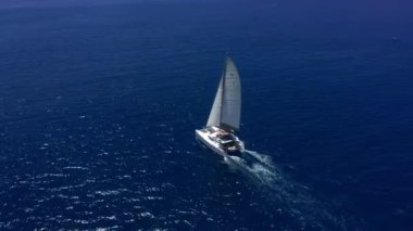 Hawaii Adaları yakınlarındaki mavi Hint Okyanusu 'nda büyük bir katamaran üzerinde seyahat edin. Lüks bir yat mavi elementin genişliğini sürüyor. Mavi denizde beyaz bir katamaranın drone görüntüsü.