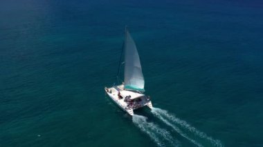 Hawaii Adaları yakınlarındaki mavi Hint Okyanusu 'nda büyük bir katamaran üzerinde seyahat edin. Lüks bir yat mavi elementin genişliğini sürüyor. Mavi denizde beyaz bir katamaranın drone görüntüsü.
