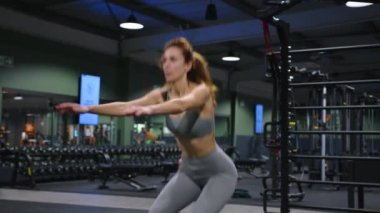 Bir kadın spor kulübünde çömelmiş spor yapıyor. Vücudunuzu formda tutmak için egzersizler. Yüksek kalite 4k görüntü