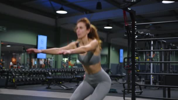 女性はスポーツクラブでスポーツスクワットをします 偉大な形であなたの体を維持するための演習 高品質4K映像 — ストック動画