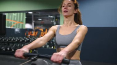 Spor salonundaki modern egzersiz aletleri. Uzun saçlı kadın güçlü ve sağlıklı vücudu için egzersiz yapıyor. Yüksek kalite 4k görüntü