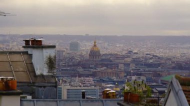 Paris 'in en yüksek noktasından şehrin manzarası. Paris 'teki evlerin çatıları bulutlu bir gökyüzüne karşı. Gün batımında Paris manzarası. Eski evlerin çatısından geçen bulutların zamanı. Yüksek kalite 4k