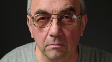 Gözlüklü yaşlı bir adam gözlüğünü çıkararak duygusal bir sürpriz yapar. Şaşırmış bir yüzü olan yaşlı bir adamın yakın plan portresi. Haberler adamı şok etti. Yüksek kalite 4k görüntü