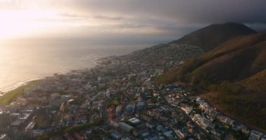 A drone flies over a modern and beautiful South African city at sunset. Aerial view of Cape Town which is located on the ocean. One of the richest cities in Africa. High quality 4k footage