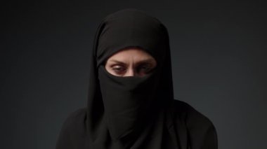 Face with natural make up of attractive muslim girl wearing traditional hijab scarf. Her brown eyes looking at camera, islam concept extreme close up 4k footage. High quality 4k footage