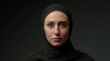 Face with natural make up of attractive muslim girl wearing traditional hijab scarf. Her brown eyes looking at camera, islam concept extreme close up 4k footage. High quality 4k footage