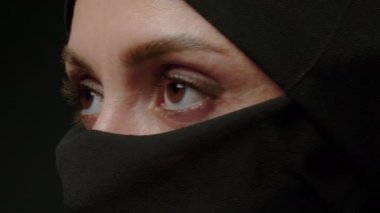 Face with natural make up of attractive muslim girl wearing traditional hijab scarf. Her brown eyes looking at camera, islam concept extreme close up 4k footage. High quality 4k footage