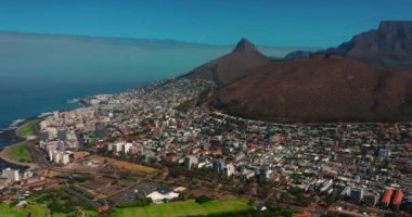 Coastal large city with a harbor on the ocean. Industrial and logistics facilities in the center of the city. Drone view of a growing city in South Africa. High quality 4k footage