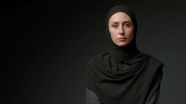 Face with natural make up of attractive muslim girl wearing traditional hijab scarf. Her brown eyes looking at camera, islam concept extreme close up 4k footage. High quality 4k footage