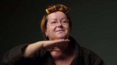 Beautiful happy mature woman doing facial face massage. Adult woman takes care of her face, does a massage and smiles. Cosmetics and procedures for mature skin and senior woman. High quality 4k