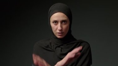 Portrait of beautiful young Arab muslim woman in black traditional hijab looking straight to camera and smiling. Close up of female pretty face with smile. Arabian headscarf. High quality 4k footage