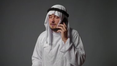 Authentic muslim businessman in traditional white kandura with beard using smartphone. Successful Saudi, Emirati, arab businessman concept. High quality 4k footage
