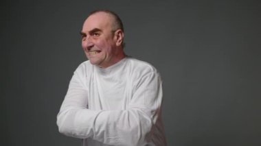 Psycho man in straitjacket have psychosis attack on gray background. Mad male patient in straitjacket is going crazy in a mental hospital. Mentally ill man with psychic disorders and bipolar disease.