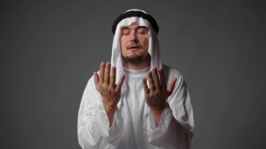 Adult Muslim man in white traditional clothes praying close-up shot, portrait. High quality 4k footage
