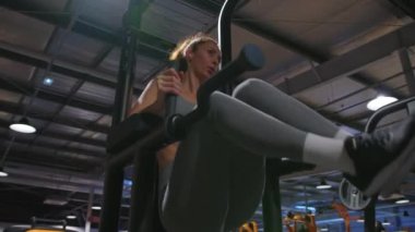 Attractive middle-aged woman takes care of the health and beauty of her body in the gym, performing sports exercises to build her body. The concept of a healthy lifestyle. High quality 4k footage
