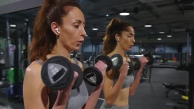 Attractive middle-aged woman takes care of the health and beauty of her body in the gym, performing sports exercises to build her body. The concept of a healthy lifestyle. High quality 4k footage