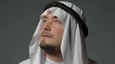 Portrait close up of successful arab man in traditional outfit, wearing white kandura and black agal looks at camera. Saudi, Emirati, Arab Businessman Concept. High quality 4k footage