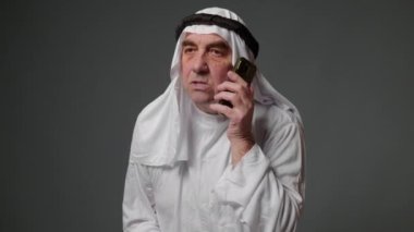 Elderly man with united arab emirates traditional clothes posing in a studio. Beautiful islamic portrait of portrait arab businessman kandur. Studio footage with different poses. High quality 4k