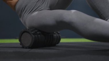 Muscle recovery after a hard workout. Close-up of a young athletic woman using a foam roller to roll out back muscles and legs. High quality 4k footage