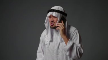 Authentic muslim businessman in traditional white kandura with beard using smartphone. Successful Saudi, Emirati, arab businessman concept. High quality 4k footage