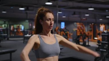 Spor kulübünde egzersiz yapan bir bayan sporcu. Sportif kız kardiyo çalışması. Koyu renk spor salonunda güçlü kadın fitness antrenmanı. Dayanıklılık için çalışan vücut geliştirici. Yüksek kalite 4k görüntü