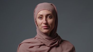 Close up portrait of independent muslim business woman looking serious confident at camera wearing traditional headscarf. Portrait muslim woman in hijab with bright makeup watching smiling.