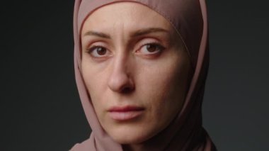 Close up portrait of independent muslim business woman looking serious confident at camera wearing traditional headscarf. Portrait muslim woman in hijab with bright makeup watching smiling.