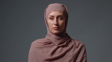 Ciddi İslamcı kadın portresi. Tatminsiz müslüman kız tesettüre bakıp inkar hareketi yapıyor. İnkar etmemek asla onaylamamak olumsuz kafa sallamayı yasaklamaz..