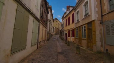 Classic medieval French facades of houses and hotels in the center of the old city not far from Paris against the backdrop of a blue sky and blue clouds. Colored buildings of old houses in France.