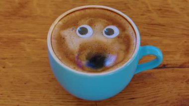 Smiling coffee man in a cup. Fragrant, lively coffee with eyes and mouth. Human face on fresh, milky coffee crema. High quality 4k footage